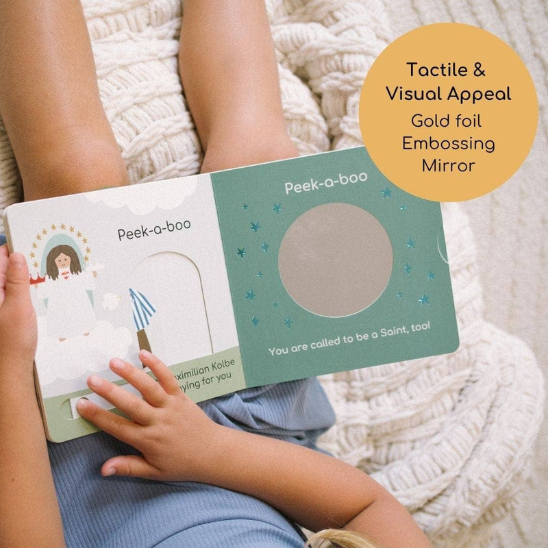 Child holding a 'Peek-a-bro' book with gold foil embossing and mirror feature, on a soft fabric background.