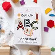 Catholic ABC Board Book surrounded by colorful blocks on a white surface