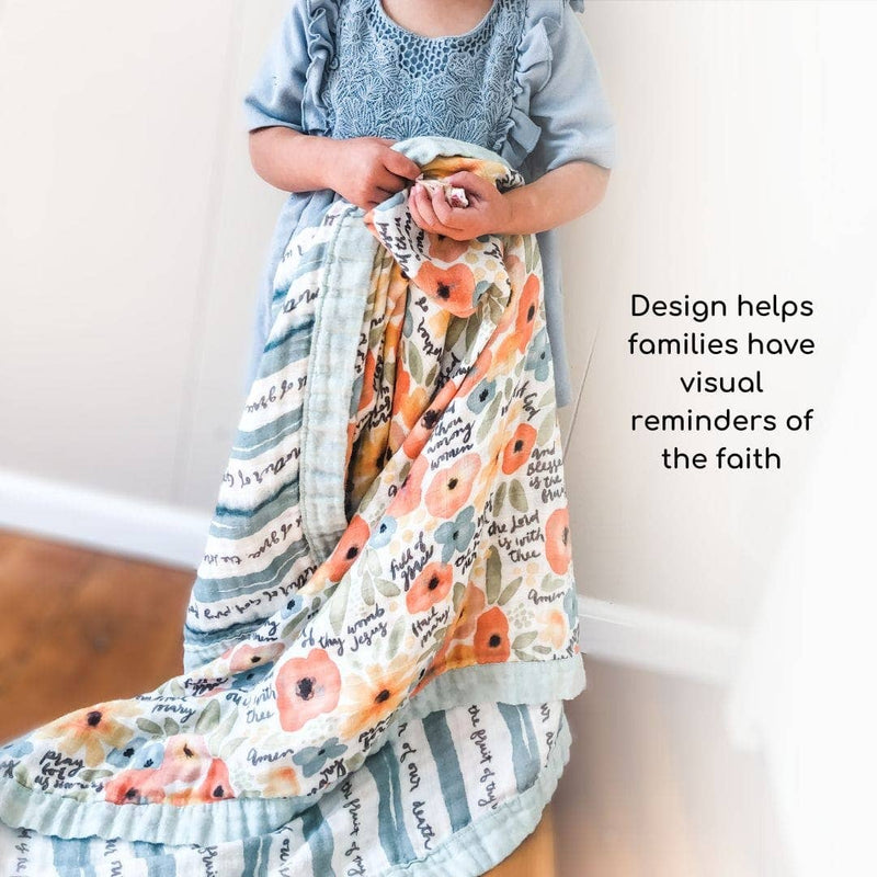 Child holding a floral-patterned blanket with text, standing against a plain background.